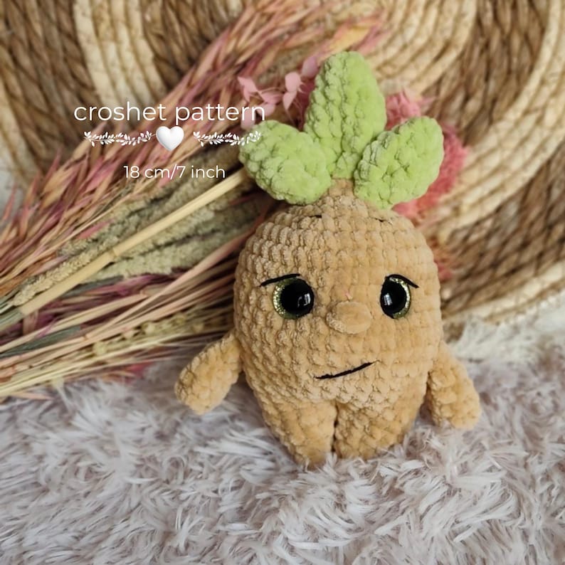 May include: A tan crochet doll with a face, arms, and legs, topped with green leaves. The doll has black eyes with gold glitter and a stitched mouth. The text "crochet pattern" and "18 cm / 7 inch" are visible.