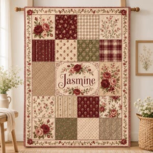 Puede incluir: Una colcha de patchwork rectangular con una variedad de cuadrados de tela en tonos burdeos, crema y verde salvia. La colcha muestra patrones florales, cuadros y lunares, con un panel central que muestra el nombre Jasmine en cursiva.