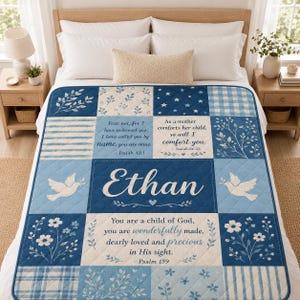 May include: A quilted blanket featuring a patchwork design in shades of blue and white. The center displays the name Ethan, surrounded by floral patterns, doves, and Bible verses including Isaiah 43:1, Isaiah 66:13, and Psalm 139 in white text.