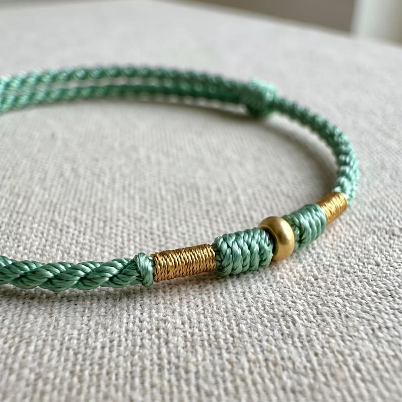 Pulsera ajustable de cordón trenzado con detalles en oro puro de 24 quilates. imagen 7