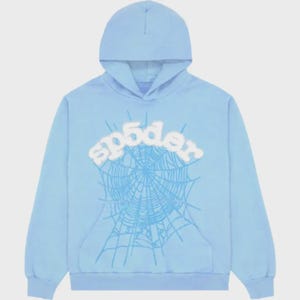 Op de afbeelding: Lichtblauwe hoodie met een voorzak en een capuchon. De voorkant toont het woord "sp5der" in wit, boven een gedetailleerd blauw spinnenwebontwerp. De hoodie is gemaakt van zacht materiaal.
