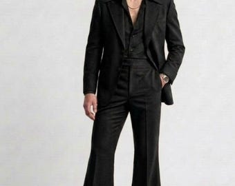 May include: A black suit with a flared leg design. The suit includes a blazer, dress shirt, and pants. The image also includes the text "- IMPERIAL ATTIRE - TAILORED TO ELEVATE -" in the upper left corner. The model is wearing a gold chain and a watch.