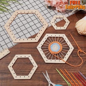 May include: A collection of wooden hexagon weaving looms in various sizes, with yarn and tools. One loom is partially woven with blue and orange yarn. A ruler, scissors, and yarn needles are also present, suggesting a craft project.