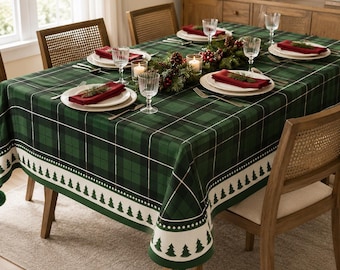 Puede incluir: Un mantel de cuadros verde oscuro y negro con un borde blanco que presenta un patrón repetitivo de pinos verdes y adornos de pompones verdes. La mesa está puesta con platos blancos, servilletas de tela rojas, cristalería y una guirnalda.