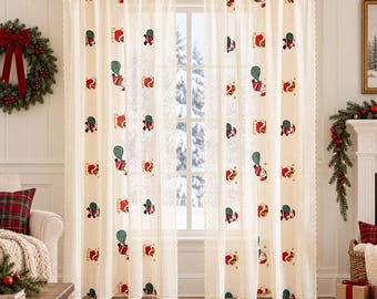 Puede incluir: Un par de cortinas semitransparentes de color blanco roto con un patrón bordado repetitivo de figuras de Santa Claus con trajes rojos y sacos de regalos verdes. Las cortinas cuelgan de una barra de madera y tienen un borde festoneado.