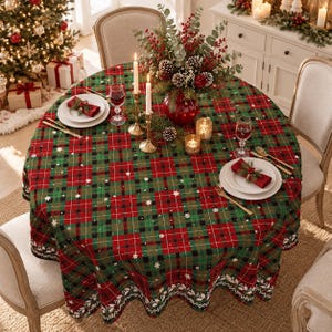 Puede incluir: Un mantel redondo con un patrón de cuadros rojos, verdes y negros con pequeños copos de nieve blancos. La mesa está puesta con platos blancos, servilletas rojas con vegetación, cubiertos dorados, dos velas altas y un centro de mesa floral.
