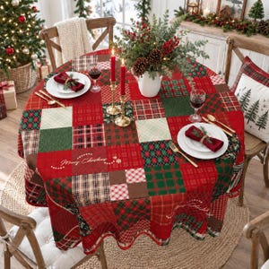 May include: A round tablecloth featuring a patchwork design of red, green, and white plaid and tartan patterns. The fabric is printed with the text Merry Christmas in gold script. The tablecloth is set with white plates, napkins, and candles.