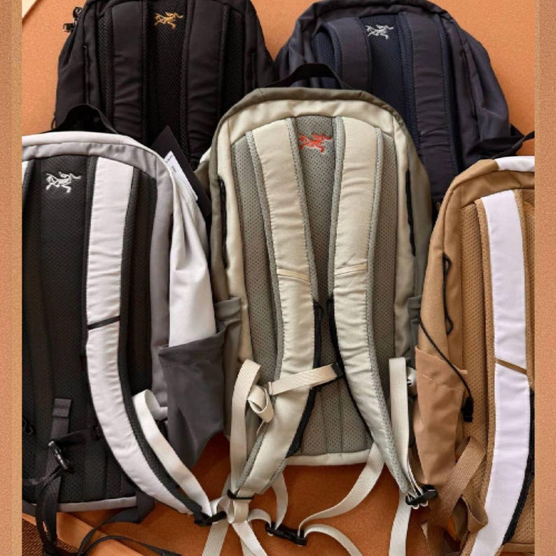May include: A collection of backpacks in various colors, including black, navy, and tan. Each backpack features a padded back panel, adjustable straps, and a logo. The backpacks are designed for outdoor activities and travel.