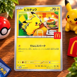May include: A yellow Pikachu trading card featuring the character sitting at a table with a burger and drink. The card displays the McDonald's logo, Japanese text, 70 HP, and electric type symbols. It is a promotional card with a silver border.