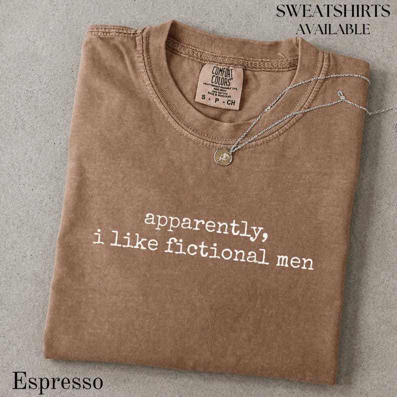 Espresso Comfort Colors sweatshirt with "apparently, i like fictional men" graphic.