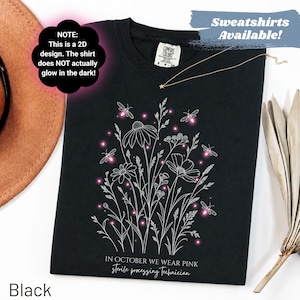 Könnte beinhalten: Ein schwarzes T-Shirt mit einer weißen Strichzeichnung von Wildblumen und Glühwürmchen mit leuchtend rosa Akzenten. Der Text lautet: NOTE: This is a 2D design. The shirt does NOT actually glow in the dark! IN OCTOBER WE WEAR PINK sterile processing technician.
