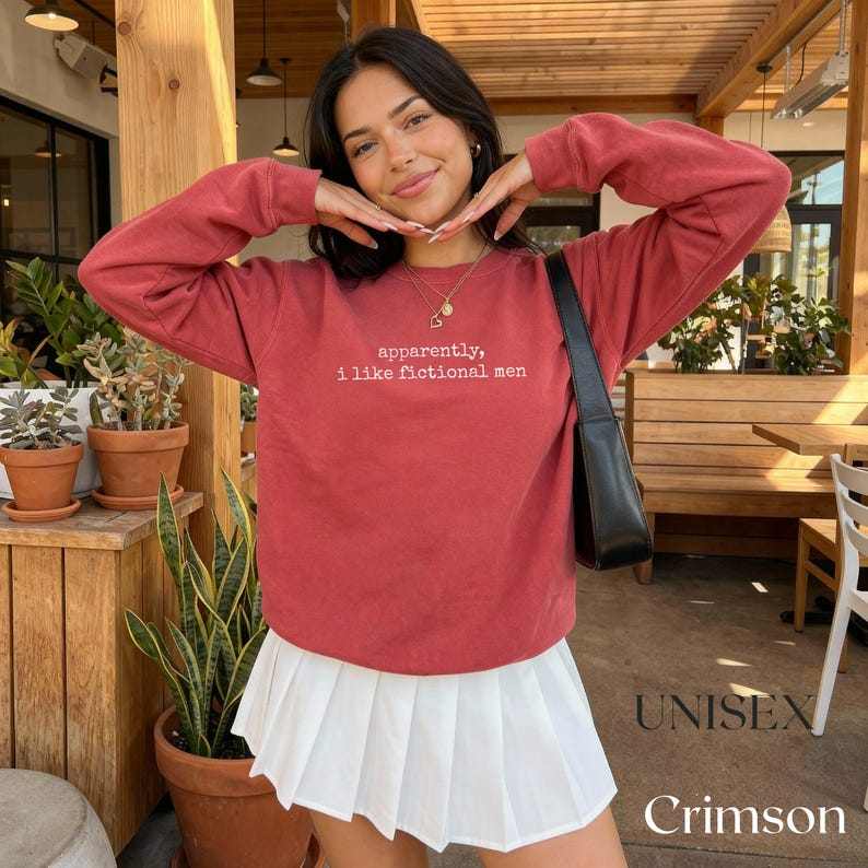 Crimson unisex sweatshirt with "apparently, i like fictional men" graphic.