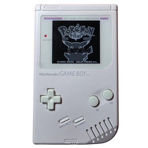Può includere: Una console portatile Nintendo Game Boy bianca con uno schermo monocromatico che mostra la schermata del titolo di Pokémon Pikachu Edition, un pad direzionale, pulsanti A e B, pulsanti Select e Start e una griglia dell'altoparlante.