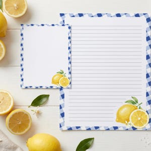 May include: A set of stationery featuring a blue and white gingham border and lemon illustrations. The set includes one small blank note card and one larger lined sheet of paper, both decorated with yellow lemons and green leaves.
