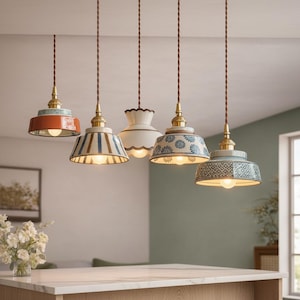 Può includere: Cinque lampade a sospensione con finiture in ottone e cavi intrecciati marroni. I paralumi presentano design vari: uno arancione tinta unita, strisce blu e bianche, un bordo smerlato bianco, un motivo floreale blu e una stampa geometrica blu.