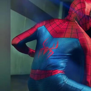 May include: A red and blue Spider-Man costume. The suit has a red spider emblem on the back and a web pattern on the red areas. The costume is close-fitting and seems to be made of a flexible material.