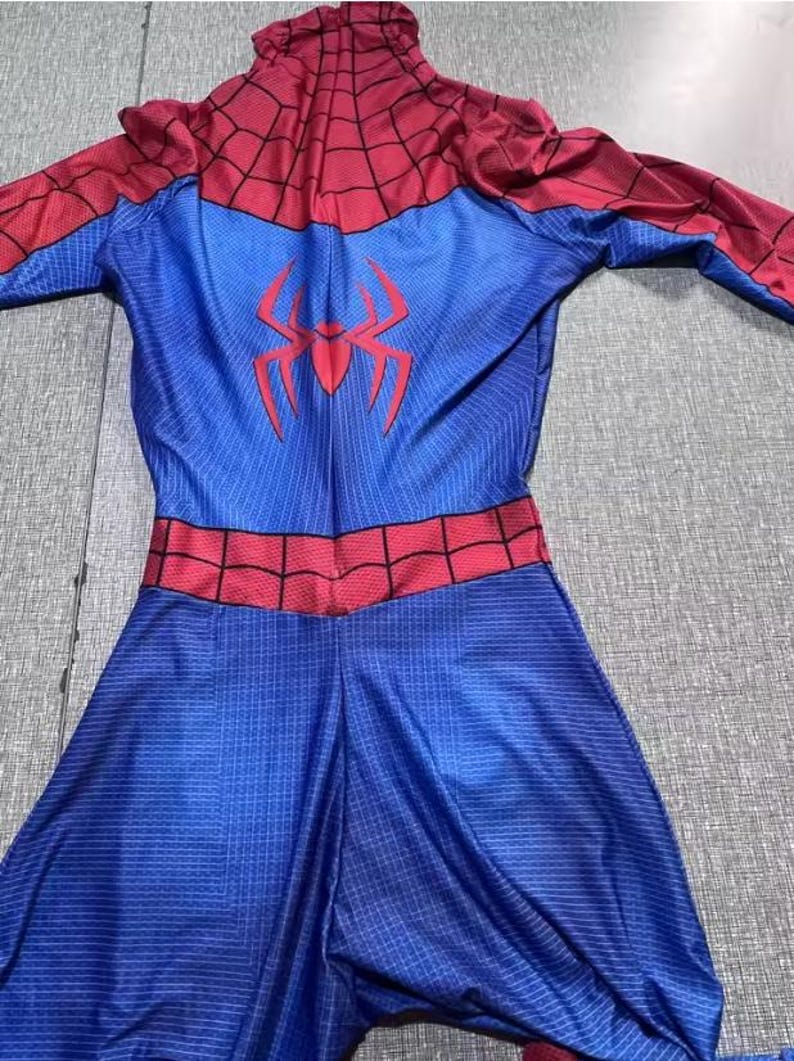 May include: A blue and red Spider-Man costume. The costume has a blue body with a red spider emblem on the back and red detailing on the shoulders and waist. It features a hood and long sleeves.