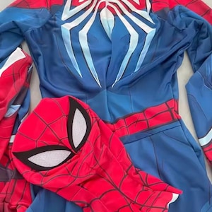 May include: A blue and red Spider-Man costume with a matching mask. The costume features a spider web design on the red areas and a large white spider emblem on the back. The mask has white eye shapes.