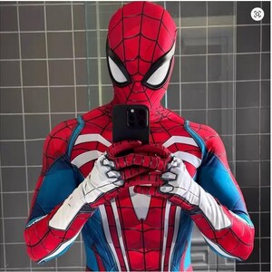 May include: A red and blue Spider-Man costume with white accents, including a full head mask and gloves. The costume is being held up by a black phone. The suit has a web-like pattern.