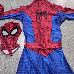 May include: A red and blue Spider-Man costume with a matching mask. The costume features a web pattern on the red areas and a black spider emblem on the chest. The mask has white eye coverings.