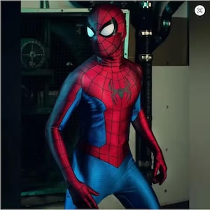 May include: A red and blue Spider-Man costume. The costume has a red torso and head with a black spider emblem, and blue arms and legs. The mask has white eye lenses. The costume is form-fitting and appears to be made of a stretchy material.