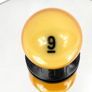 Peut inclure: Une boule de billard jaune avec le numéro 9 imprimé en noir dessus.