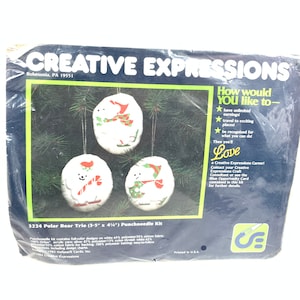 May include: Punchneedle kit to create three polar bear ornaments. The kit includes white fabric, yarn, and instructions. The bears are wearing red and green holiday attire. The package says "Creative Expressions" and "3224 Polar Bear Trio (3-5" x 4") Punchneedle Kit".