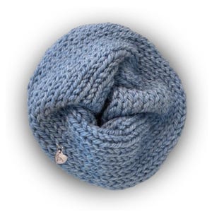 May include: A light blue infinity scarf made of thick, chunky knit yarn. The circular scarf features a textured, braided stitch pattern and includes a small, silver-toned heart-shaped metal charm attached to the side with the word "love" engraved.