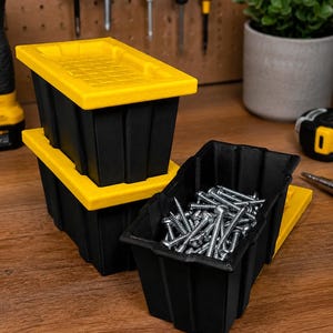 Puede incluir: Contenedores de almacenamiento negros y amarillos con tapas, apilados sobre una superficie de madera. Un contenedor está lleno de tornillos plateados. Herramientas cuelgan en el fondo, sugiriendo un taller.