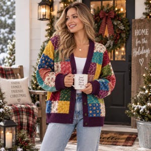 May include: A long-sleeve button-down cardigan featuring a multi-coloured patchwork floral pattern in shades of yellow, red, green, and blue, with solid dark purple trim on the cuffs, hem, and placket, worn over a white top and blue jeans.