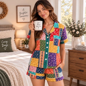 May include: A short-sleeve button-down pajama shirt and matching shorts set featuring a colorful patchwork design with various floral and geometric patterns in shades of yellow, red, green, blue, and purple, finished with white piping trim.