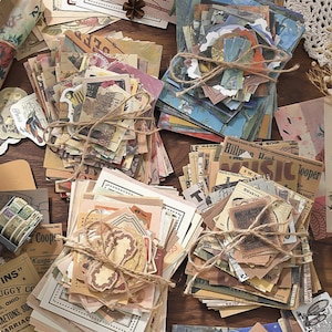 May include: A collection of vintage paper ephemera, including labels, tickets, and newspaper clippings, tied with twine. The papers feature various colors and designs, creating a collage-like aesthetic. Some items have text, such as "INS" and "Coope".