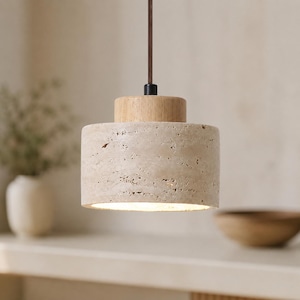 Könnte beinhalten: Eine zylindrische Pendelleuchte mit hellbeigem Steinschirm und Holzaufsatz. Das Licht hängt an einem braunen Kabel. Die Leuchte ist von innen beleuchtet und erzeugt einen warmen Schein.
