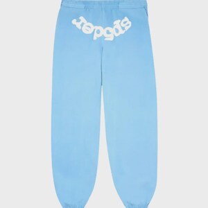 May include: Light blue sweatpants with the word "spider" in white, arched across the back waistband. The pants have a relaxed fit and a drawstring waist. The fabric appears to be a lightweight material.