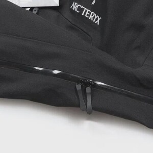 May include: A close-up of a black jacket featuring a zipper and the brand name "ARC'TERYX" in white. The jacket is made of a smooth, matte material. The zipper has two pulls.