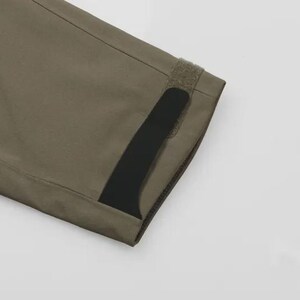 May include: Detail of olive-green fabric, possibly a sleeve. A black stripe and velcro fastening are visible. The material is smooth and likely durable. The image is set against a plain white background.