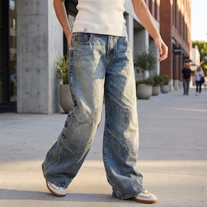 May include: Light blue denim jeans with a wide-leg design. The jeans have a faded wash and unique stitching details on the knees. The person is wearing white sneakers with a brown sole. The jeans are a casual style.