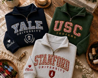 May include: Three quarter-zip sweatshirts in navy blue, forest green, and light gray. Each features university names in red or blue gingham applique, embroidered crests, and personalized names on the sleeve cuffs with heart icons.