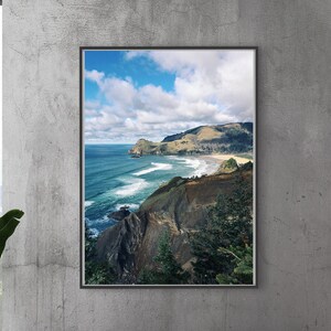 May include: A framed photograph of a coastal landscape with a rocky cliffside, green hills, and a blue ocean with white waves. The sky is blue with white clouds.