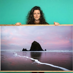 May include: A framed photograph of a rocky island in the ocean at sunset. The sky is a soft pink and purple, and the water is calm and reflective. The island is silhouetted against the sky.