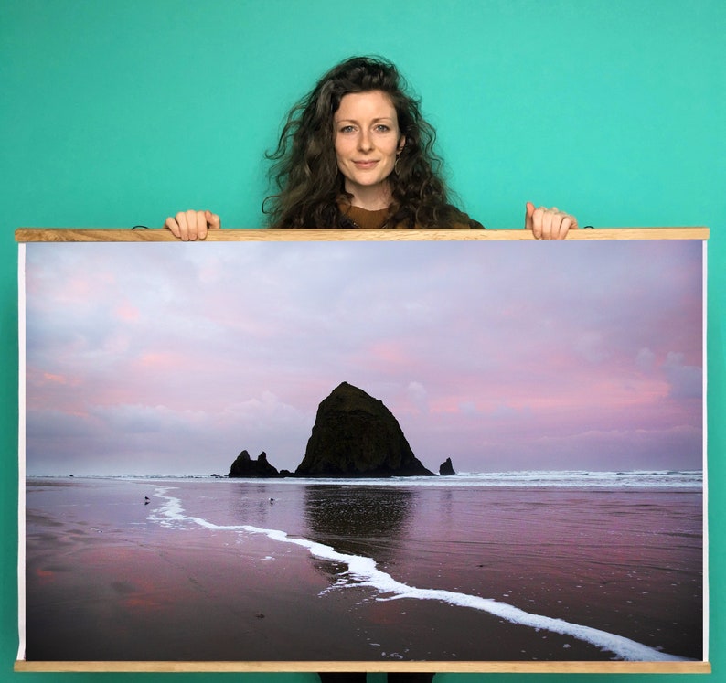 May include: A framed photograph of a rocky island in the ocean at sunset. The sky is a soft pink and purple, and the water is calm and reflective. The island is silhouetted against the sky.