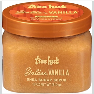 Puede incluir: Un tarro de exfoliante de az&uacute;car y karit&eacute; Tree Hut Golden Vanilla. El tarro tiene una tapa de bronce y un cuerpo transparente, lleno de un exfoliante marr&oacute;n dorado. La etiqueta presenta las palabras "Golden Vanilla" y "Shea Sugar Scrub", con un peso neto de 510 g.