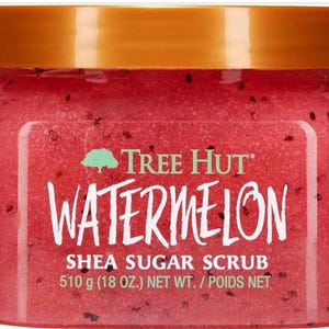 Puede incluir: Un tarro de exfoliante de az&uacute;car de karit&eacute; de sand&iacute;a Tree Hut. El tarro transparente tiene una tapa dorada y contiene un exfoliante rojo con motas negras. El peso neto es de 510 g.