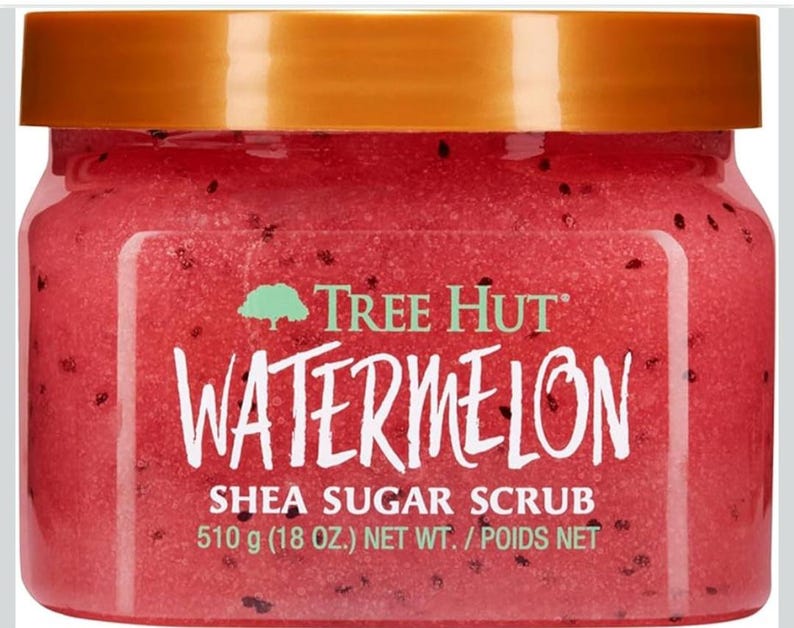 Puede incluir: Un tarro de exfoliante de az&uacute;car de karit&eacute; de sand&iacute;a Tree Hut. El tarro transparente tiene una tapa dorada y contiene un exfoliante rojo con motas negras. El peso neto es de 510 g.