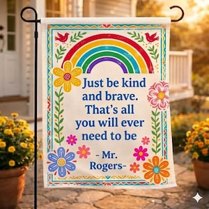 以下が含まれることがあります： 虹のデザインと「Just be kind and brave. That's all you will ever need to be - Mr. Rogers-」というテキストが特徴の装飾的なガーデンフラッグ。 フラッグには花のボーダーがあり、屋外に展示されています。