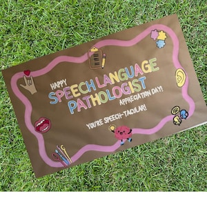 May include: A brown paper sign with the words "Happy Speech Language Pathologist Appreciation Day!" in colorful lettering. A pink wavy line surrounds the text and includes various illustrations, such as a brain, ear, and mouth.