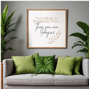 May include: A living room setting with a grey sofa and green cushions. A framed print displays the text "Exceedingly & Abundantly More... Than you can Imagine". Potted plants are positioned on either side of the sofa, enhancing the decor.