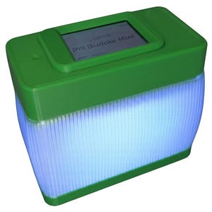 Puede incluir: Un dispositivo rectangular verde con una peque&ntilde;a pantalla que muestra "Pill Buddie Mini". La parte inferior del dispositivo es transl&uacute;cida y emite un brillo azul. El dispositivo tiene una forma redondeada.