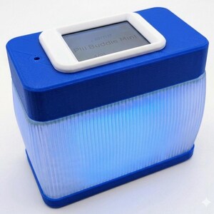 Puede incluir: Un dispositivo Pill Buddie Mini azul y blanco. La parte superior es azul con una pantalla rectangular blanca que muestra texto. La secci&oacute;n inferior es un dise&ntilde;o transl&uacute;cido y acanalado que brilla con luz azul.