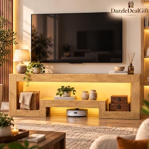 May include: A light wood television console with integrated warm LED lighting, featuring a lower shelf, a woven basket, two small decorative boxes, potted plants, and a robotic vacuum cleaner positioned underneath the center shelf.